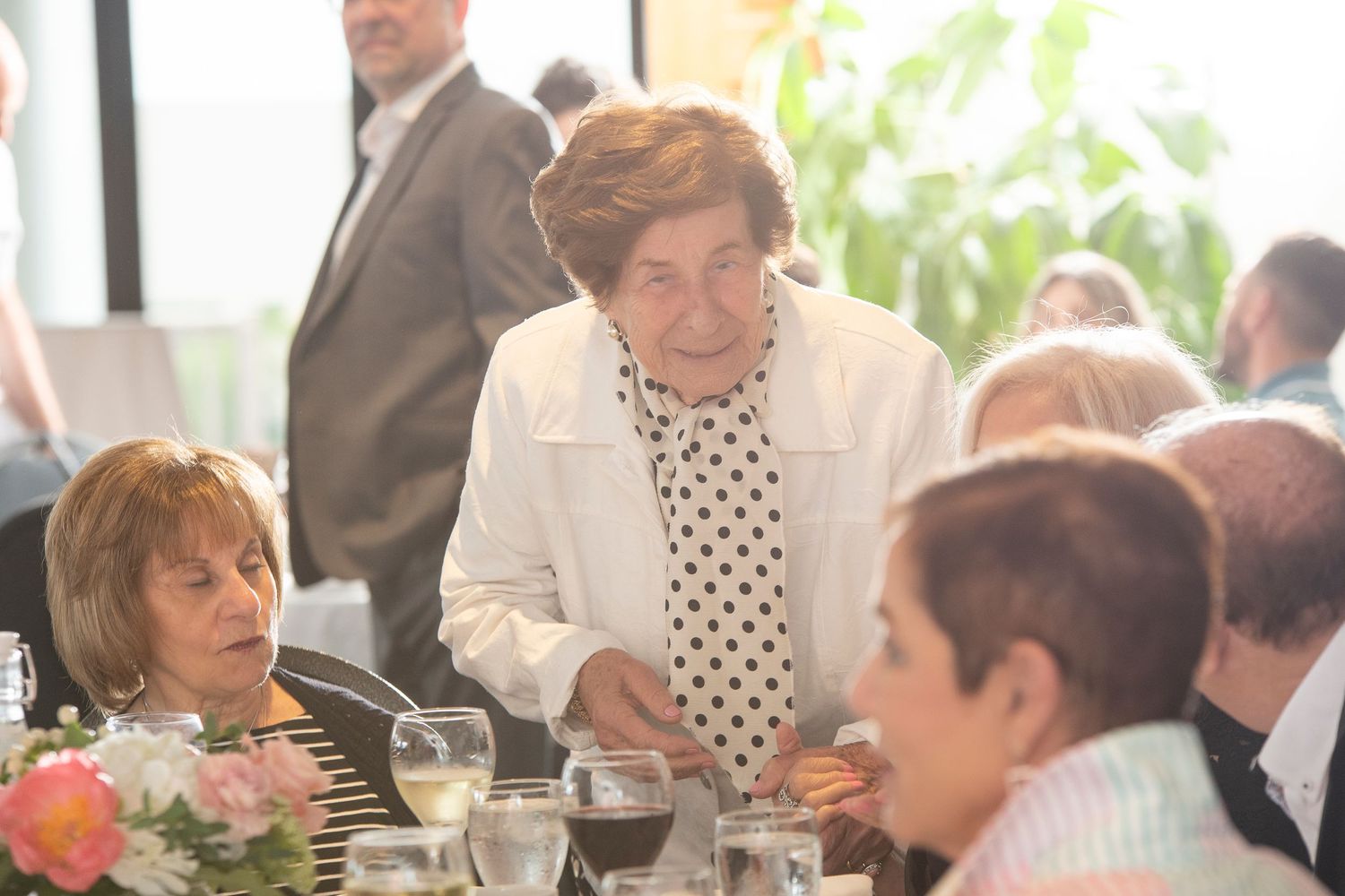 Guests gathered around elegant dining tables at a formal celebration event.