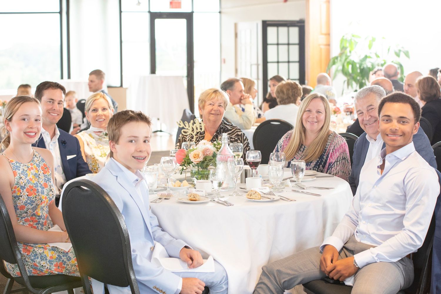Guests seated at round tables during formal dining event with bright natural lighting.