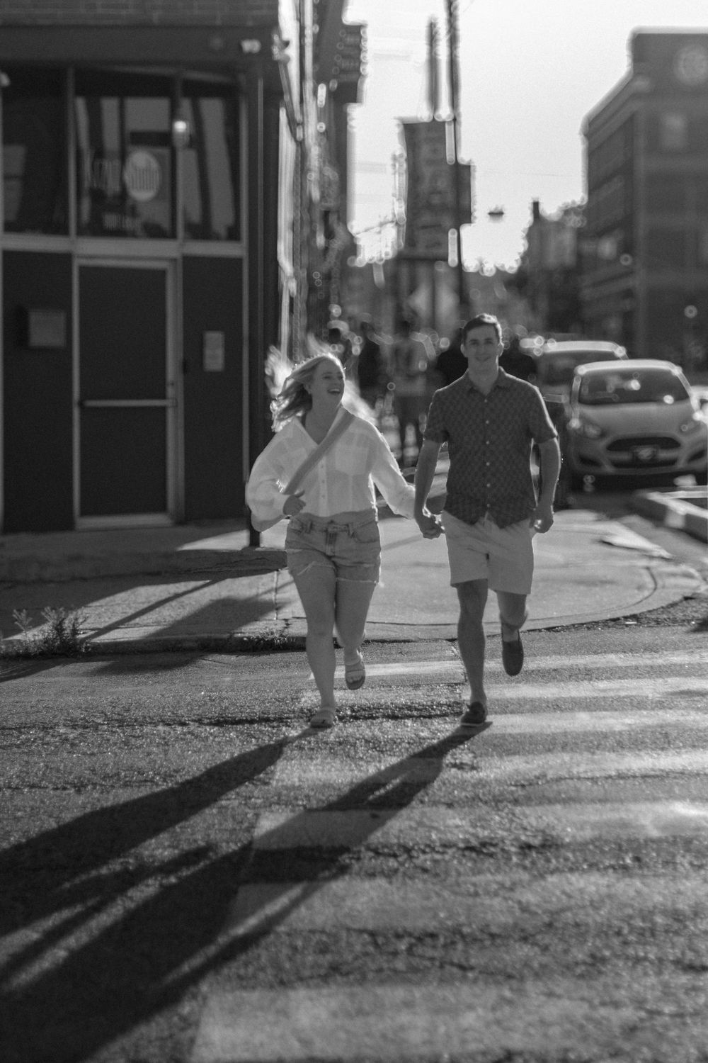 Black and white photo of people walking on a street casting long shadows.