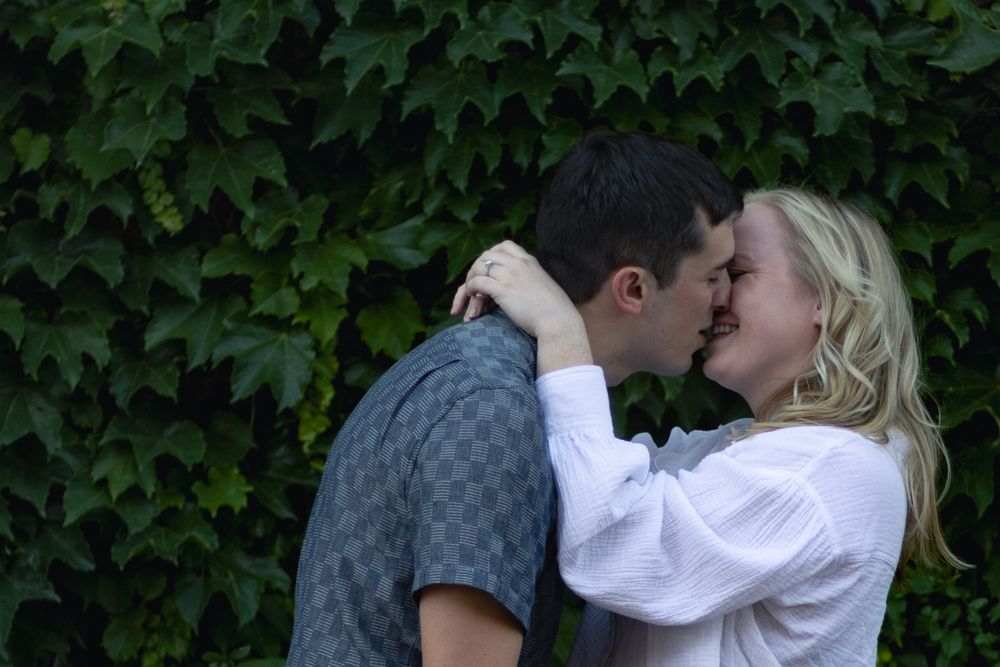 A romantic moment captured between a couple against green foliage.