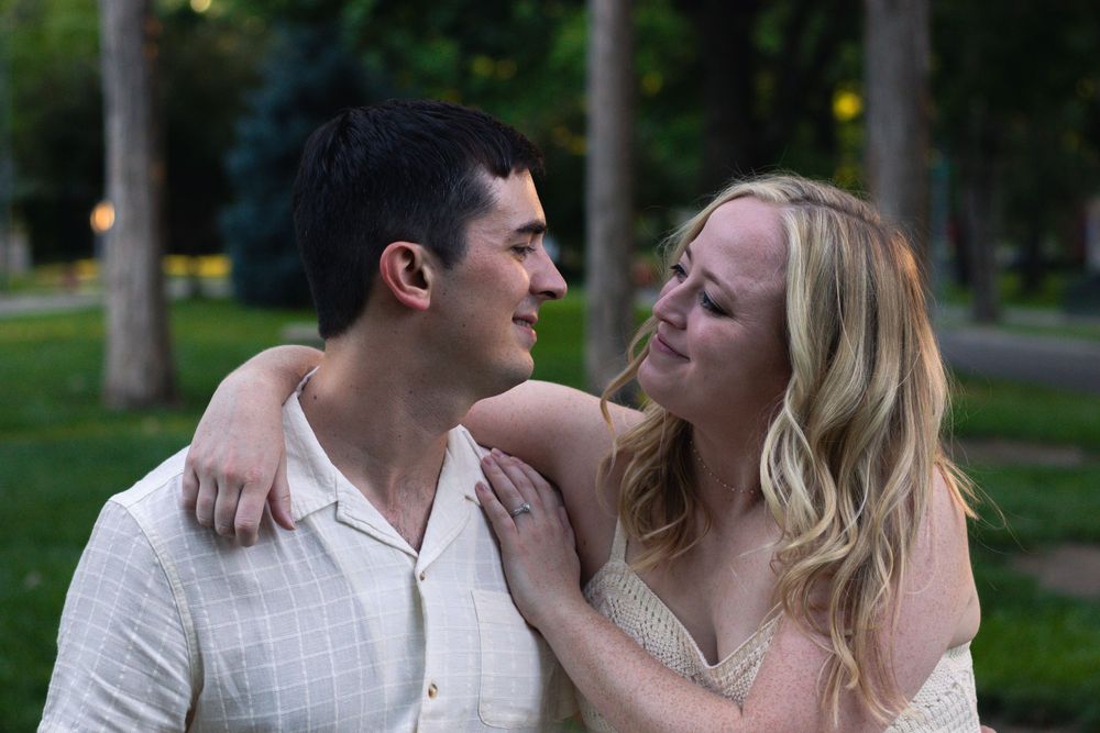 A romantic couple embraces on a park path during golden hour.