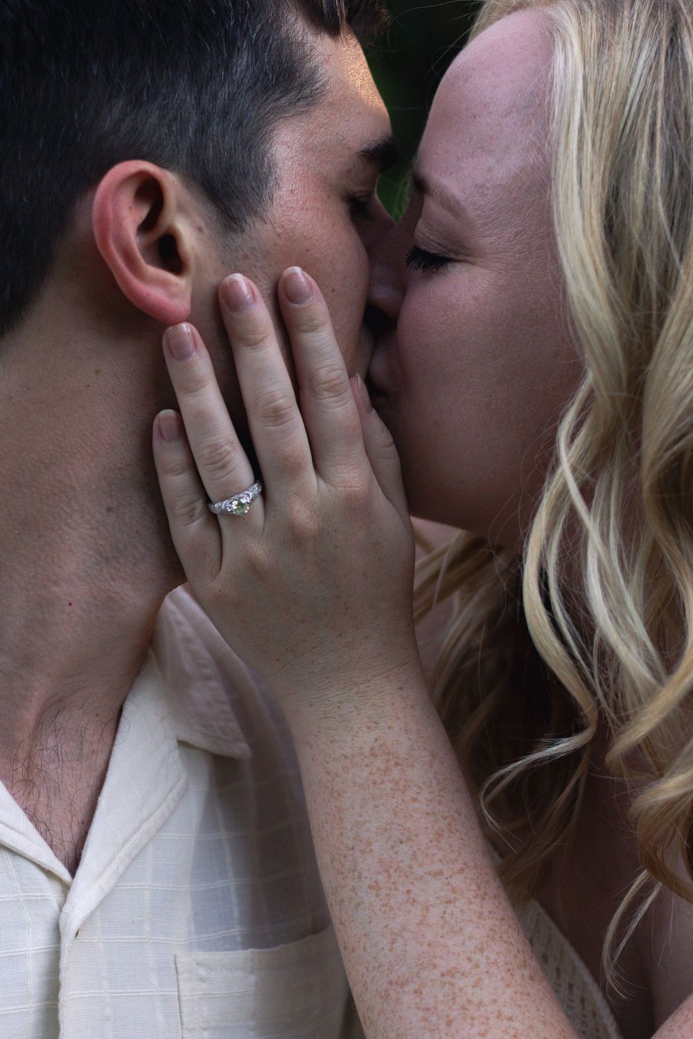 A tender moment between a couple sharing a kiss outdoors.