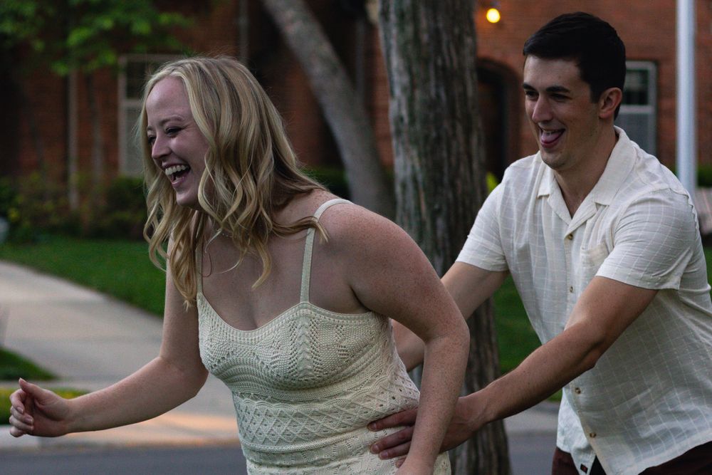 A couple enjoys a playful moment together outdoors at dusk.