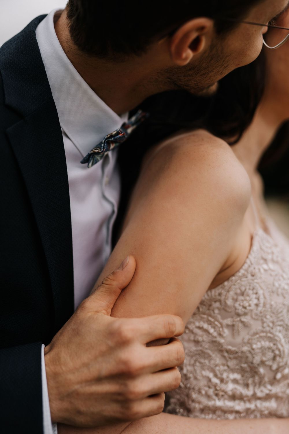 Close-up detail shot of hands and lace during an intimate wedding moment.