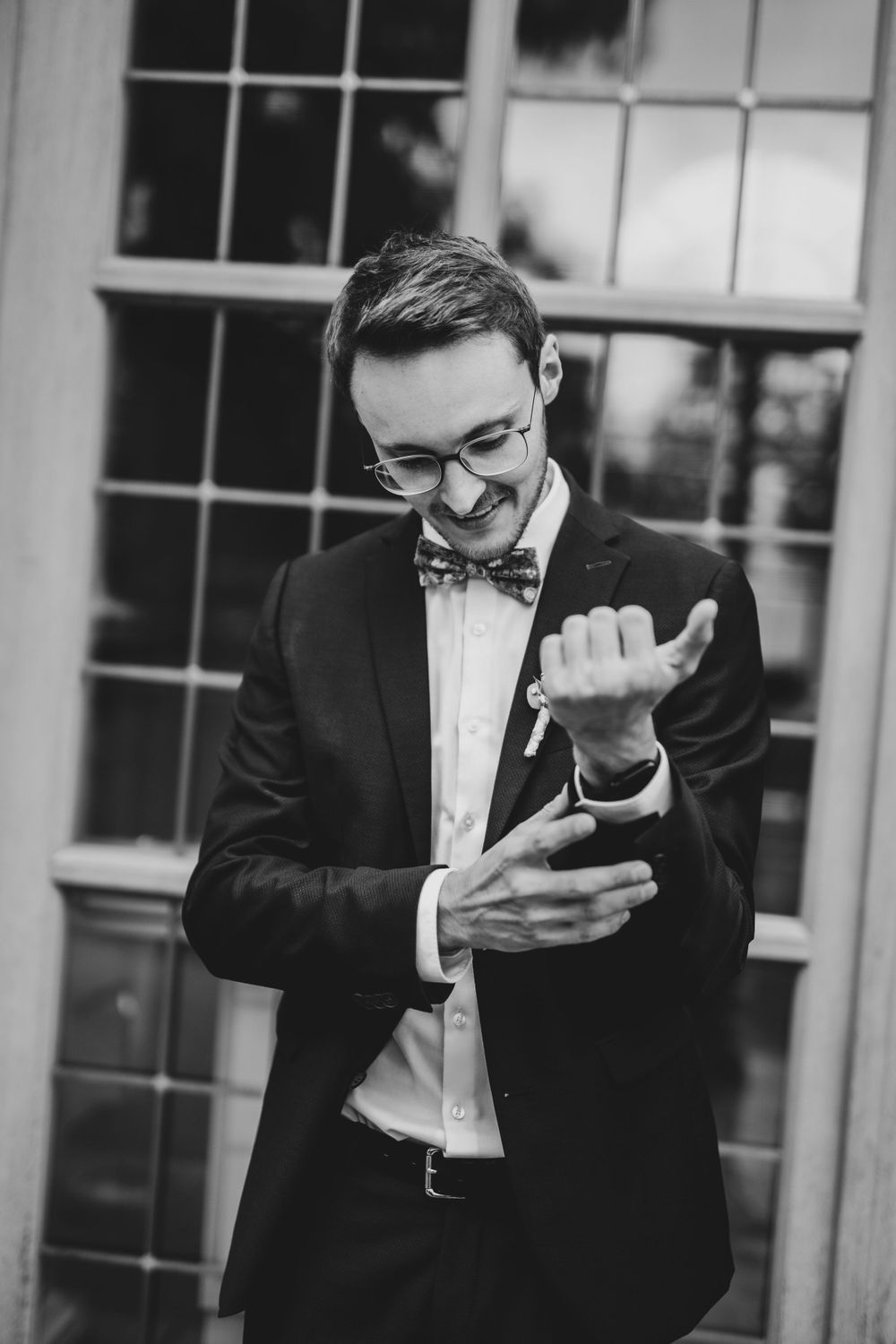 Person in formal attire checks their phone during wedding preparations.