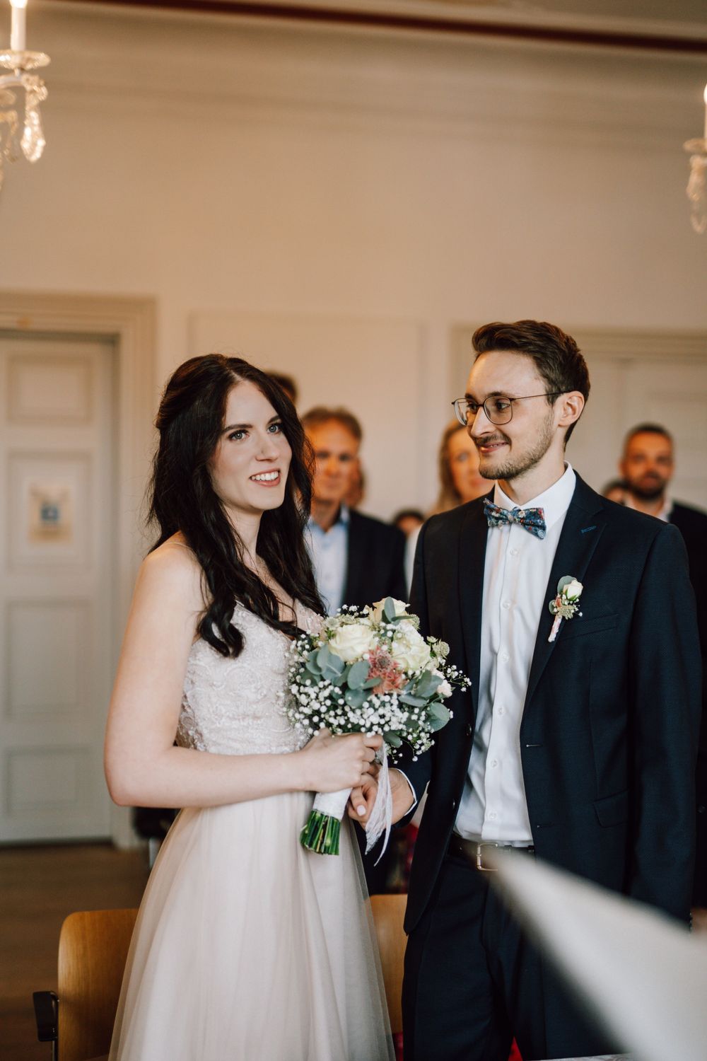 Wedding couple exchanges joyful glances during their indoor ceremony.