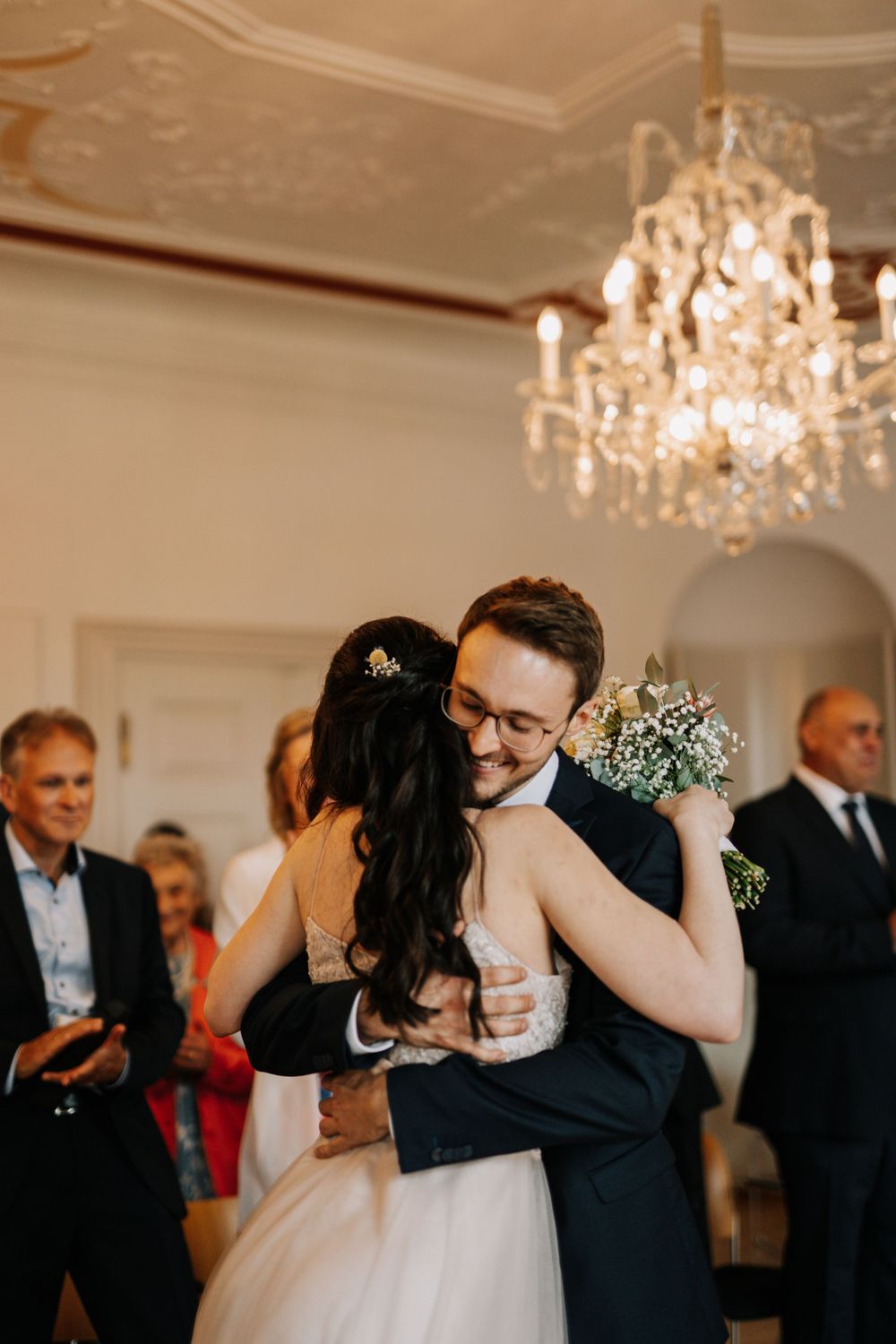 A couple shares their first dance under an elegant crystal chandelier.