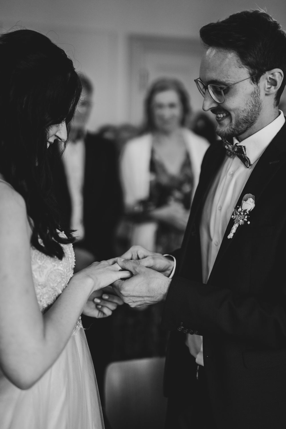 A couple exchanges rings during an indoor wedding ceremony.