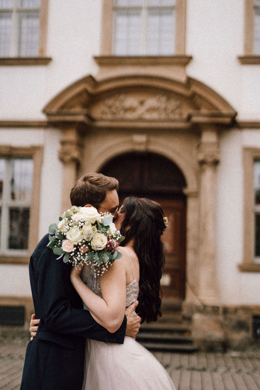A romantic moment captured between newlyweds outside an elegant building entrance.