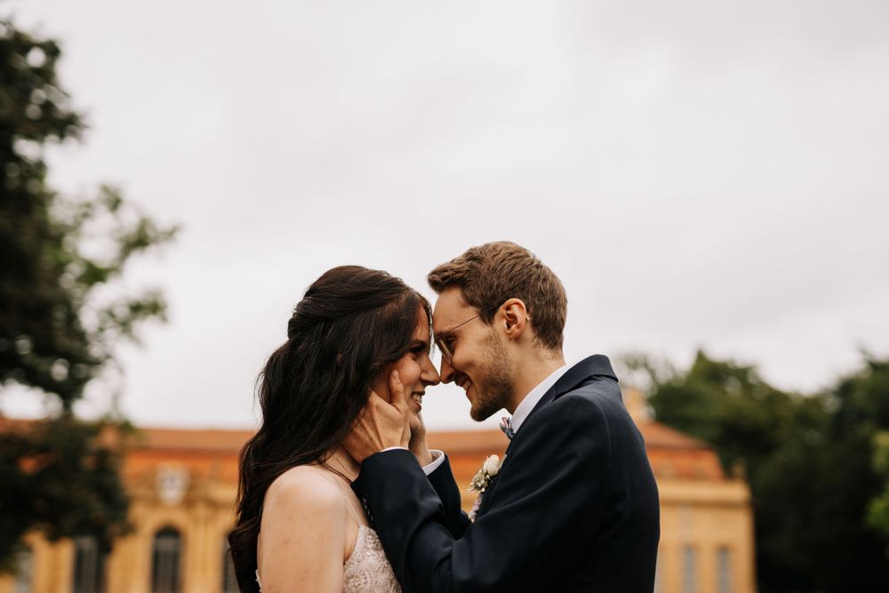 Romantic wedding portraits taken outside a historic building with cloudy skies.