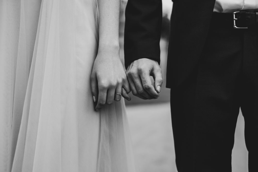 Black and white detail shot of wedding attire and hands.