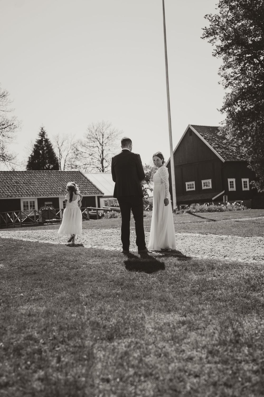 Black and white photo of wedding ceremony outside a rustic barn building.