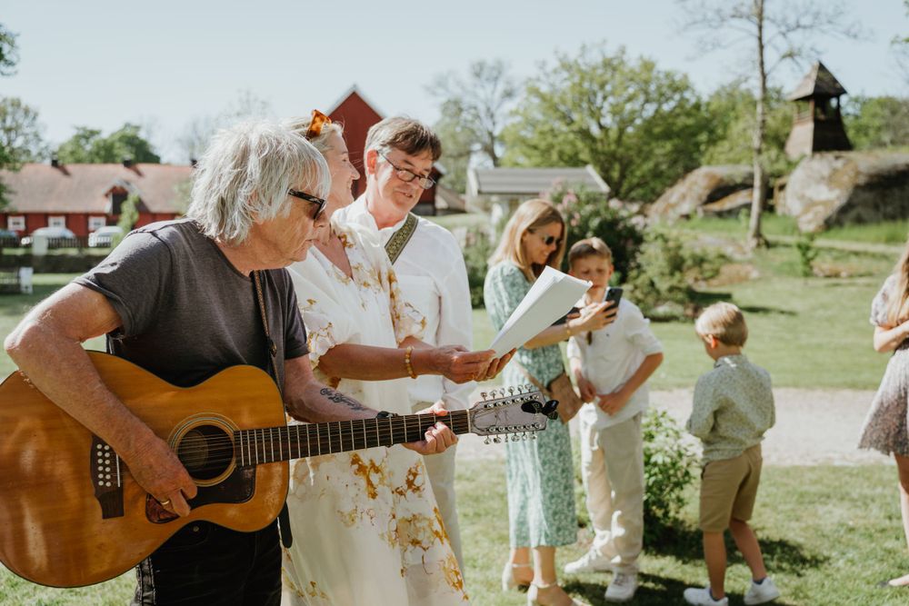 Outdoor wedding celebration with acoustic guitar performance in a garden setting.
