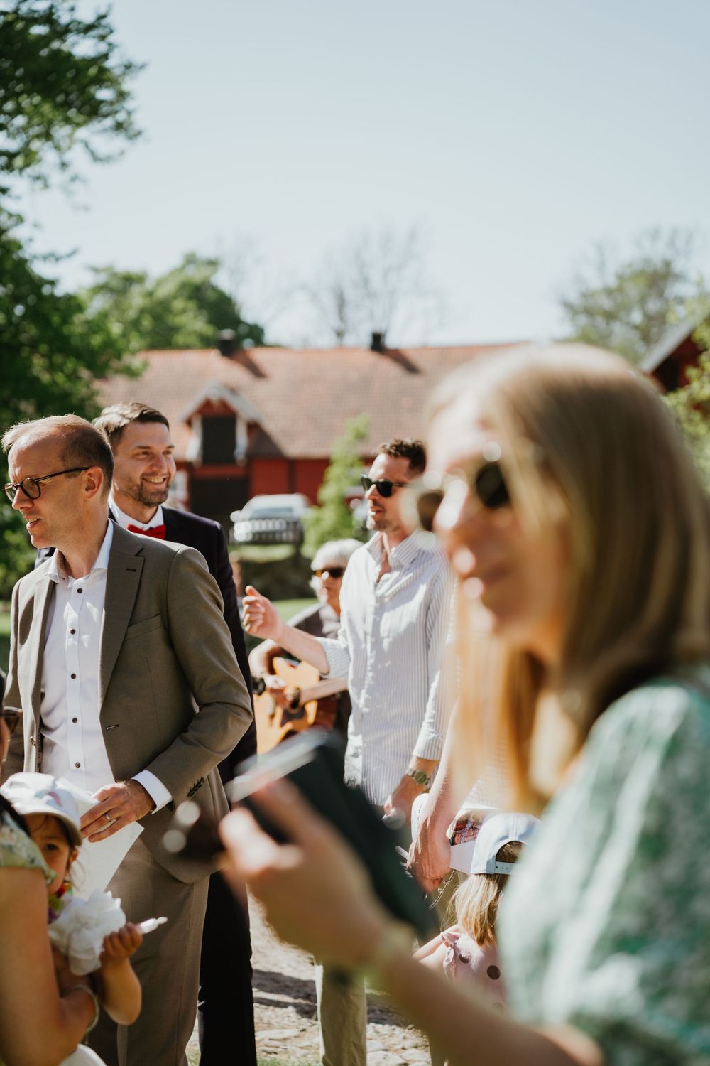 Candid shot of wedding guests enjoying themselves at an outdoor summer celebration.