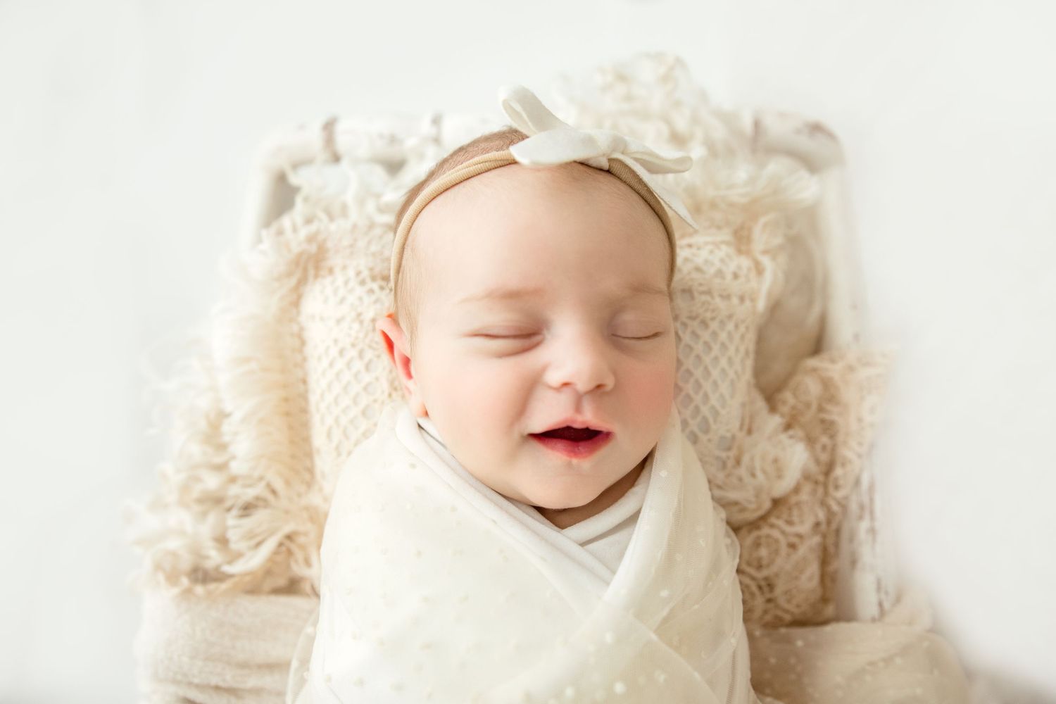 A sleeping newborn baby swaddled in cream-colored fabric lying on a textured beige blanket..  Middle TN Newborn Photographer.