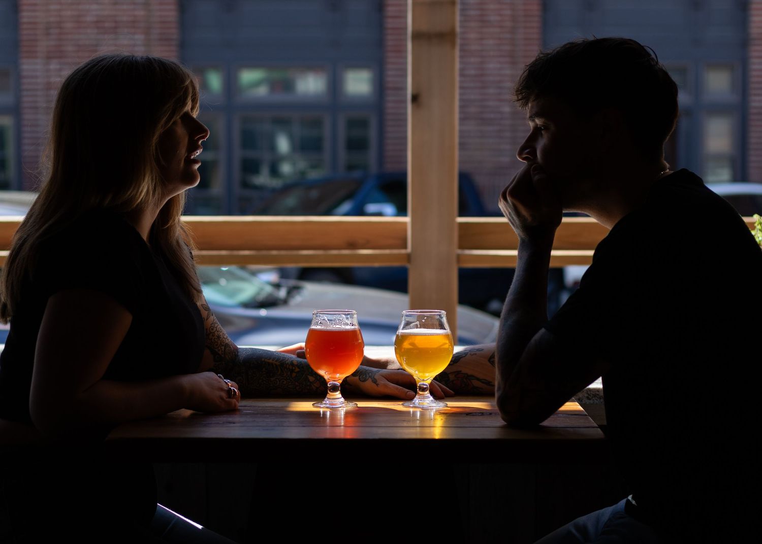 Dark silhouettes of patrons at a bar with brick walls and warm lighting.