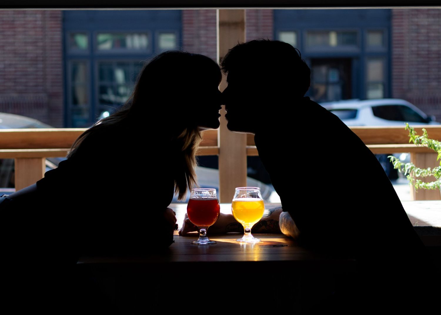 Atmospheric bar setting with shadowy figures and colorful cocktails on counter.