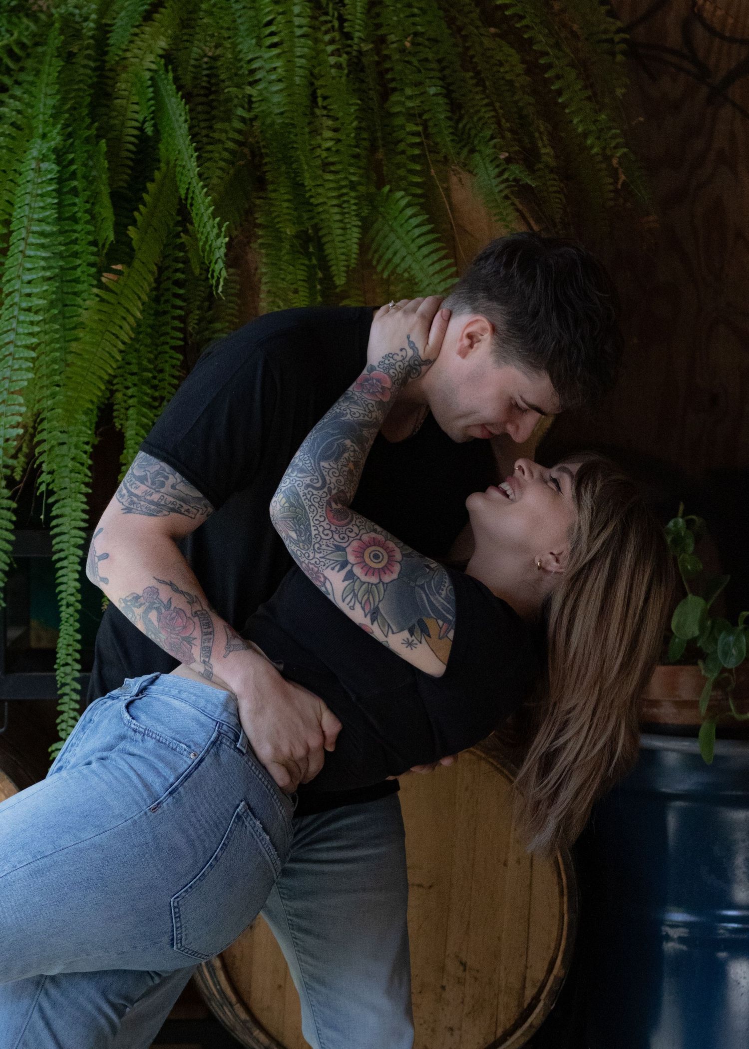Couple embracing near hanging ferns in a cozy indoor setting.