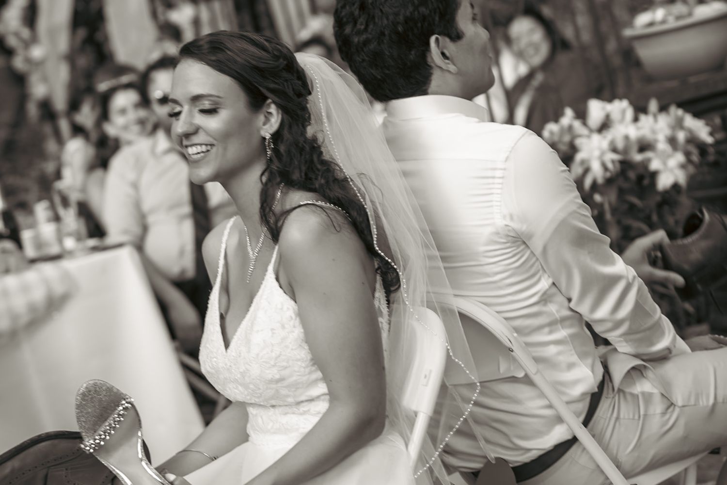 Black and white candid photo of newlyweds sharing a joyful moment at their reception.