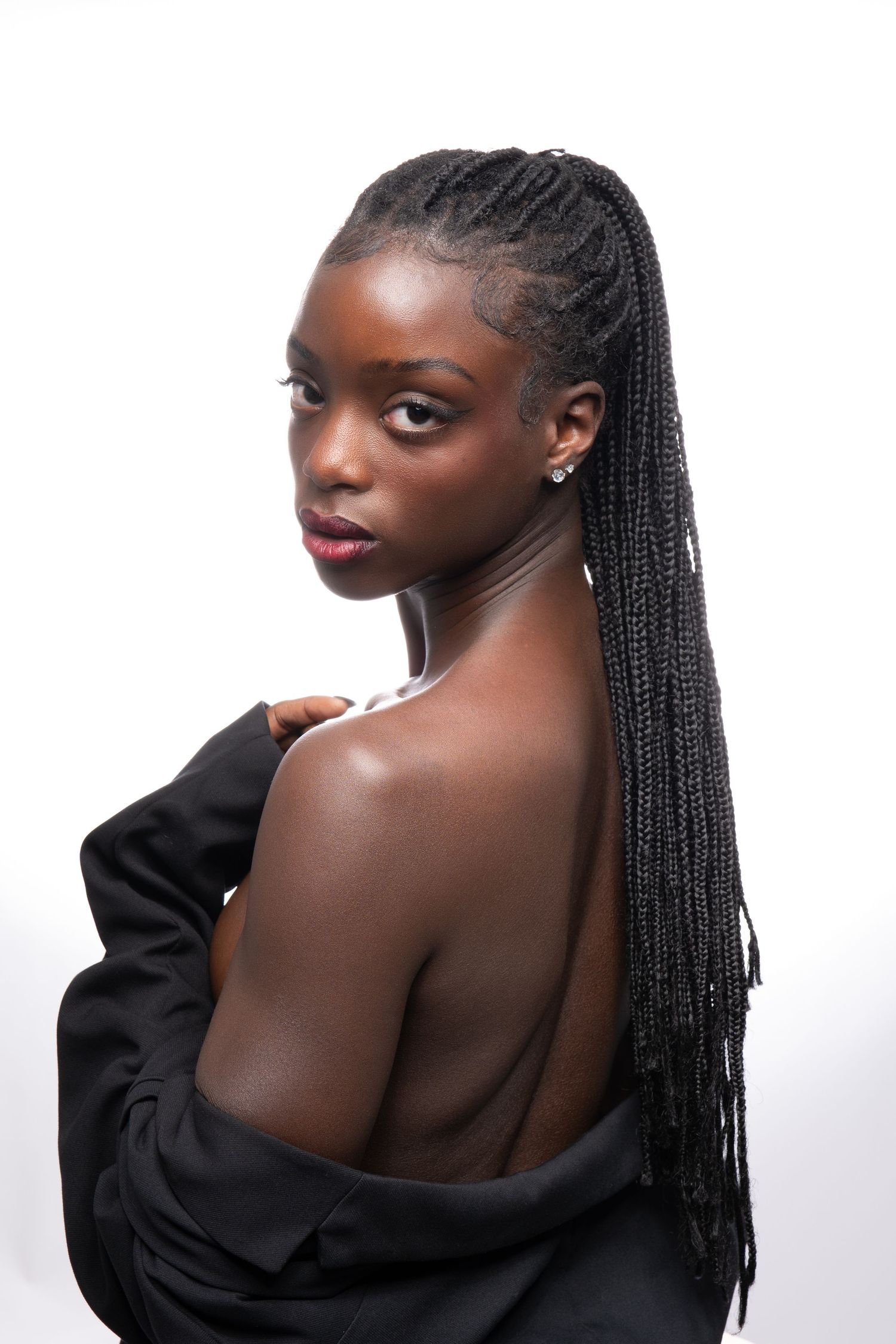 Elegant portrait showing bare shoulders and long braided hair with black draping fabric.