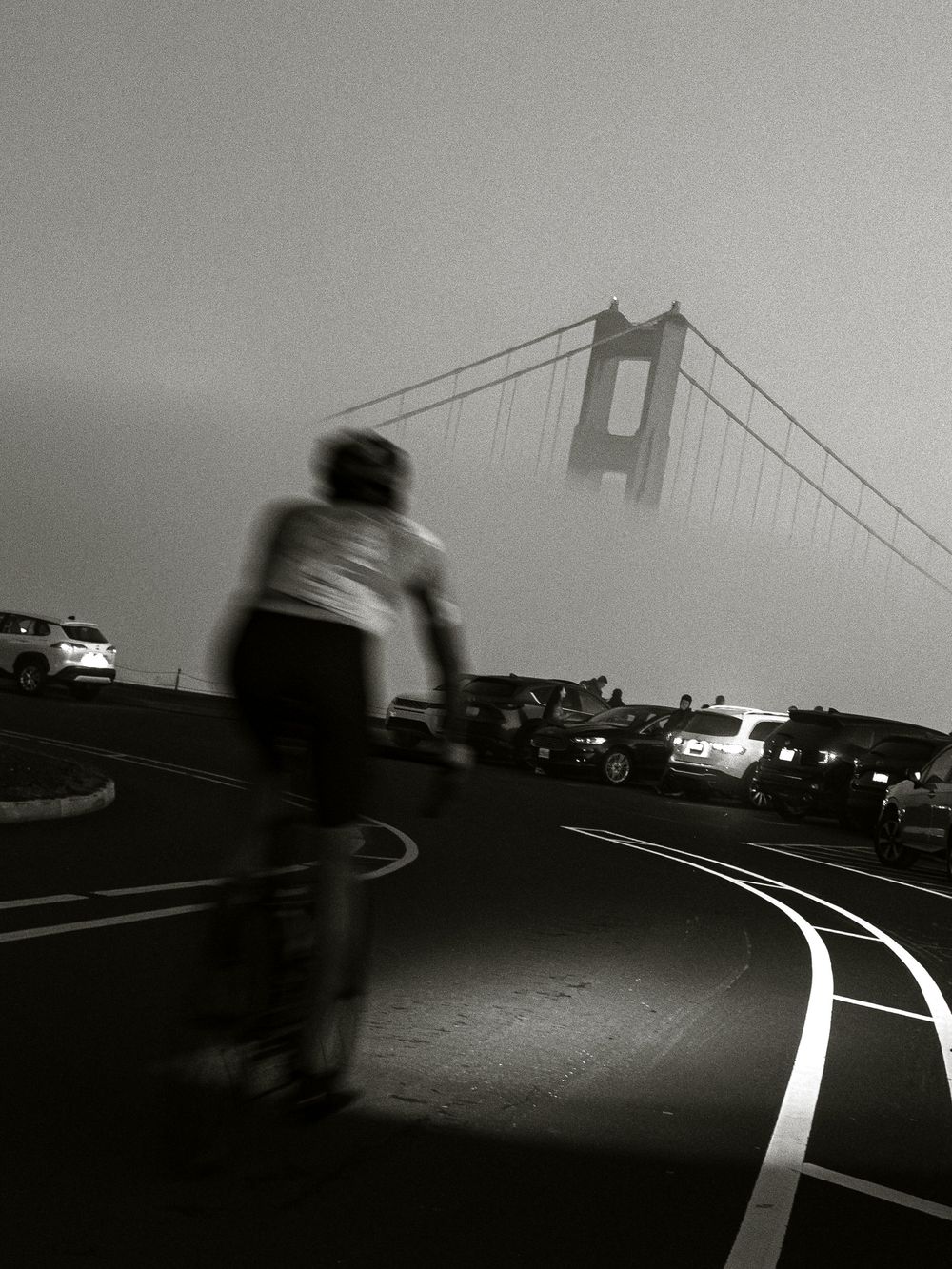 Silhouette of a cyclist against the foggy Golden Gate Bridge at dusk.