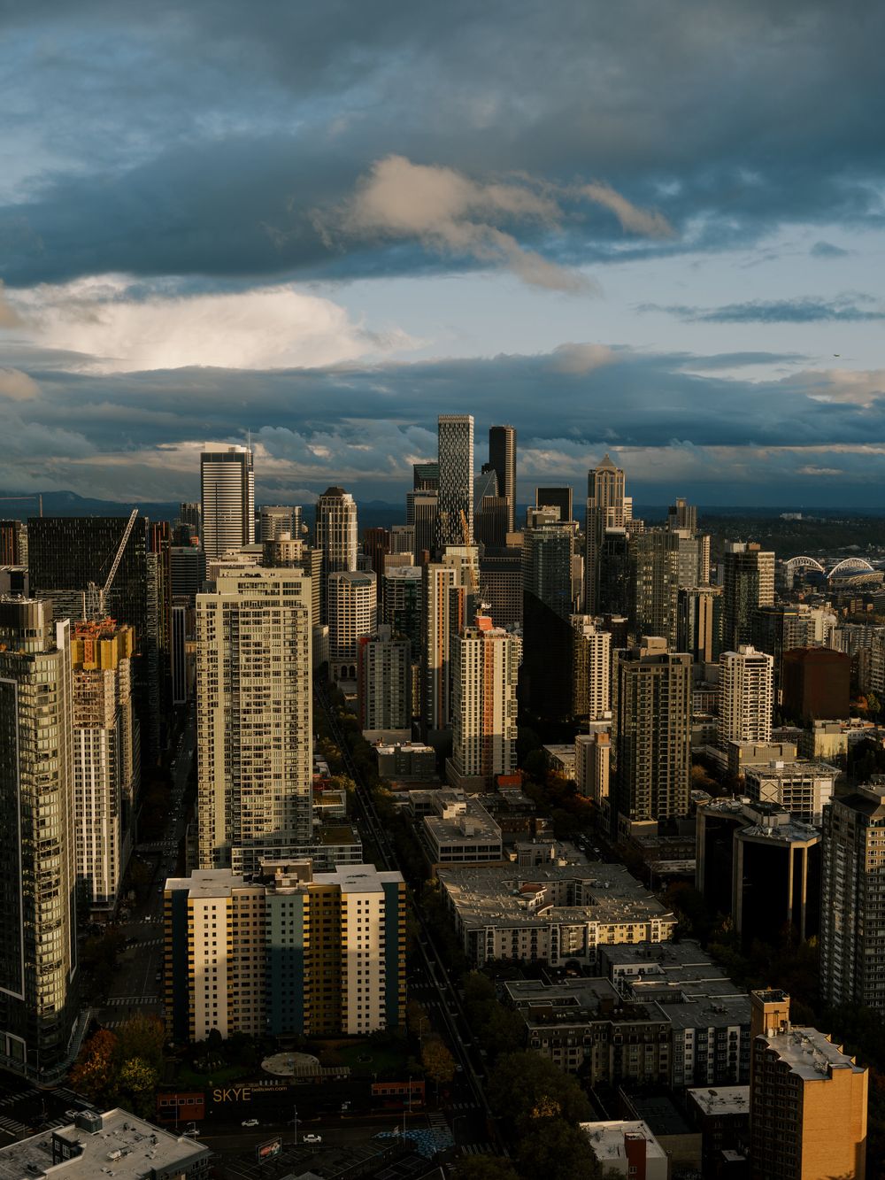 Dramatic cityscape of downtown Vancouver under stormy skies during golden hour.
