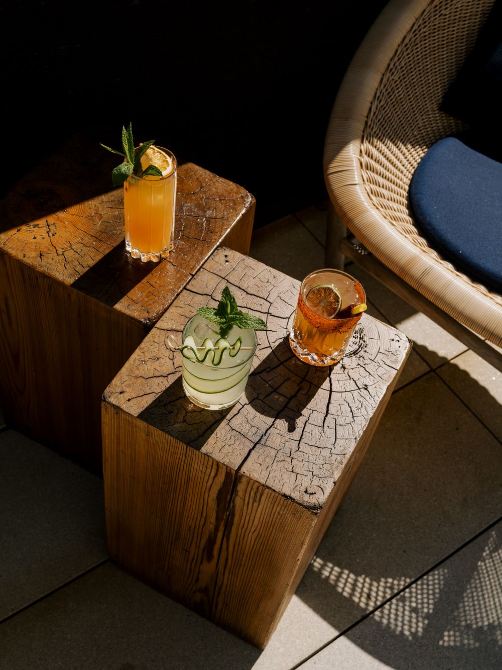A timelapse sequence shows different cocktails with citrus garnishes on rustic wooden blocks against a dark background.