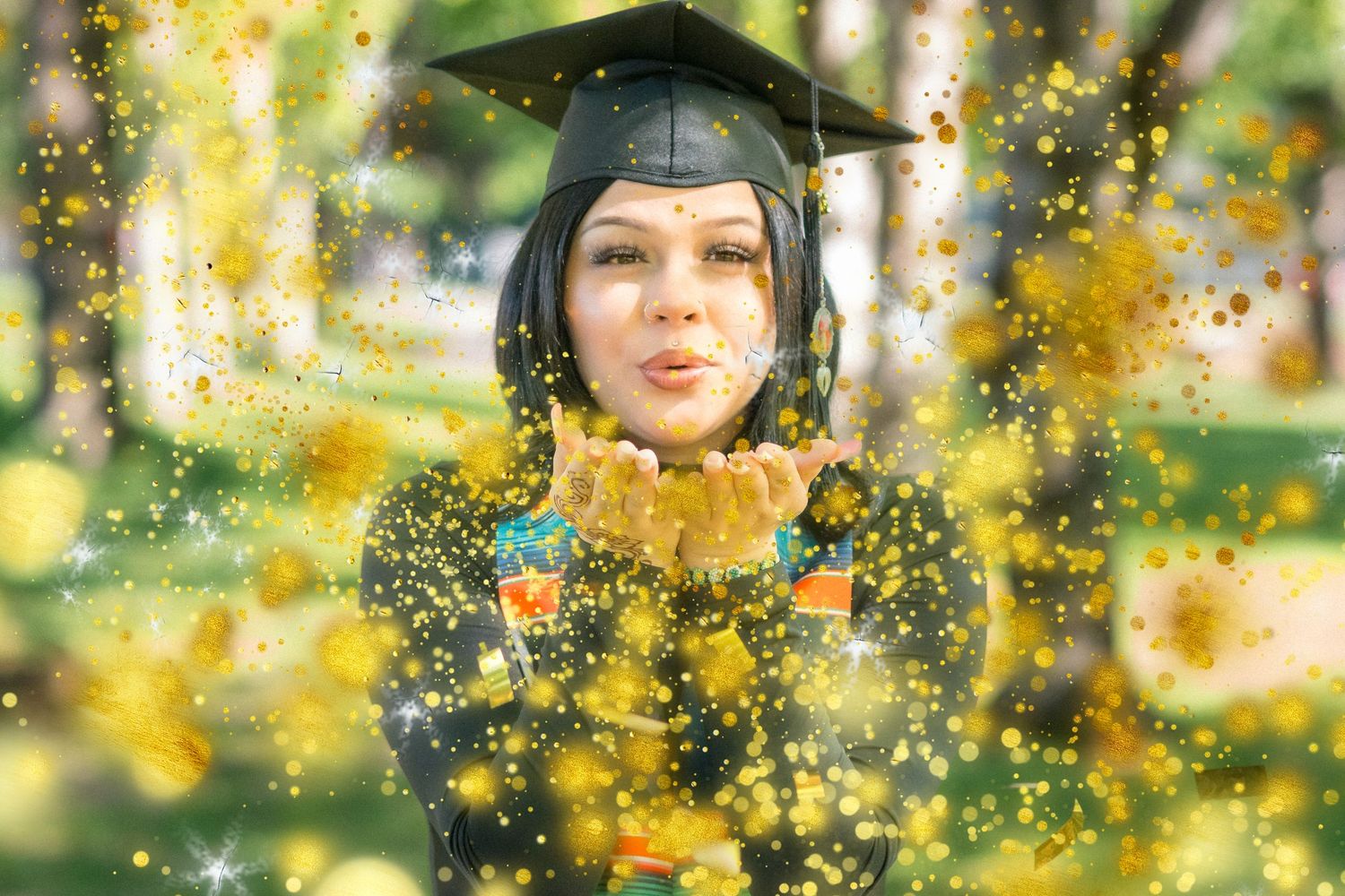 Graduate in cap and gown surrounded by magical golden bokeh effects.