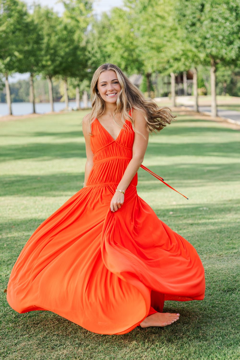 Twirling coral maxi dress creates movement in outdoor park setting.