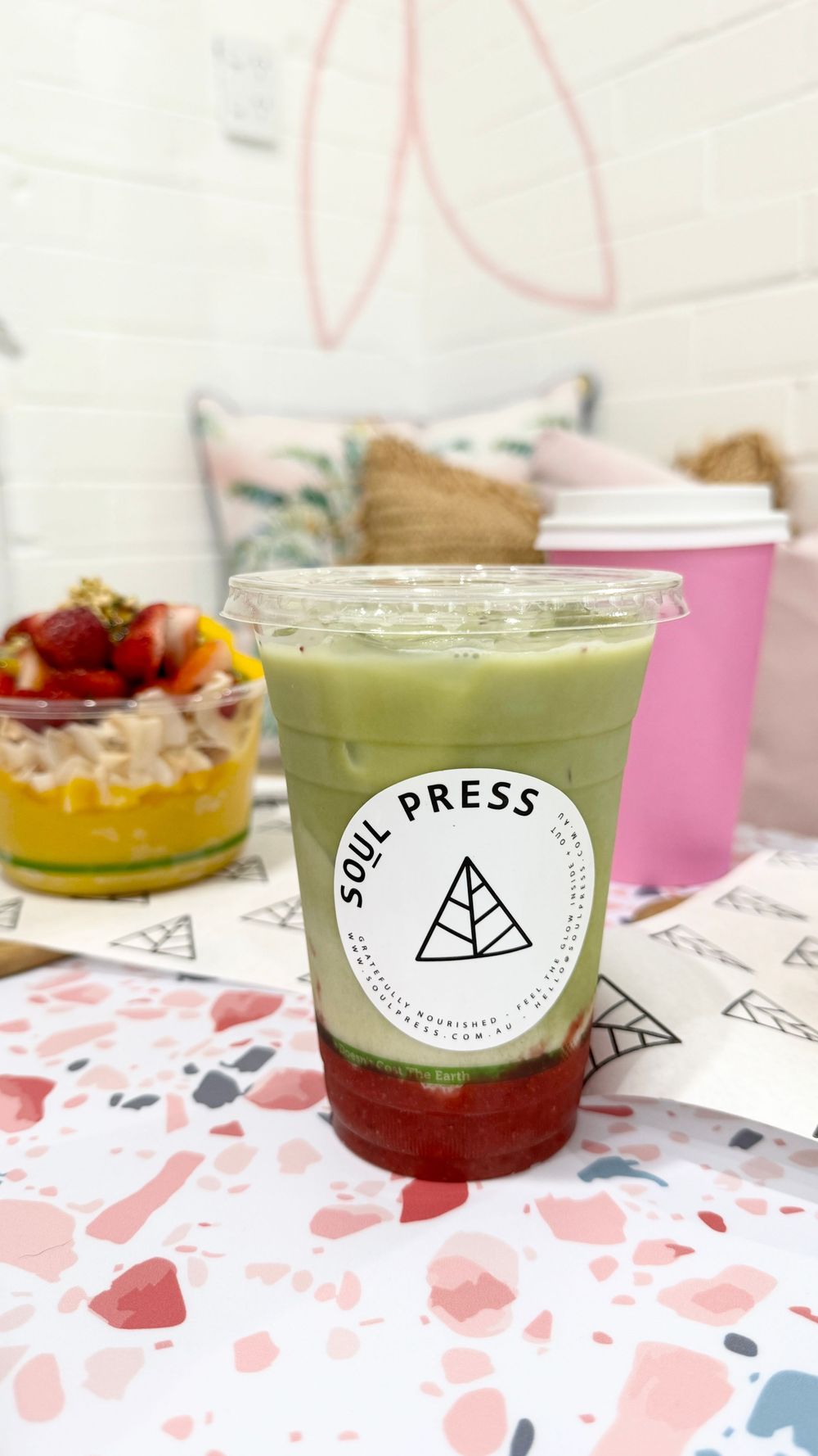 Soul Press branded beverage with green matcha and red layers on a decorative table setting.