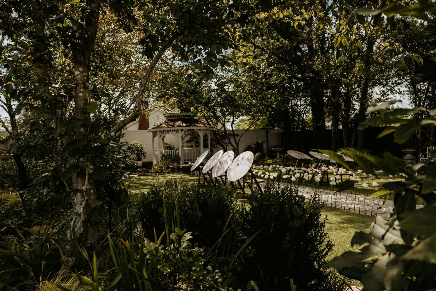 Garden wedding ceremony setup with rows of chairs among trees and foliage.