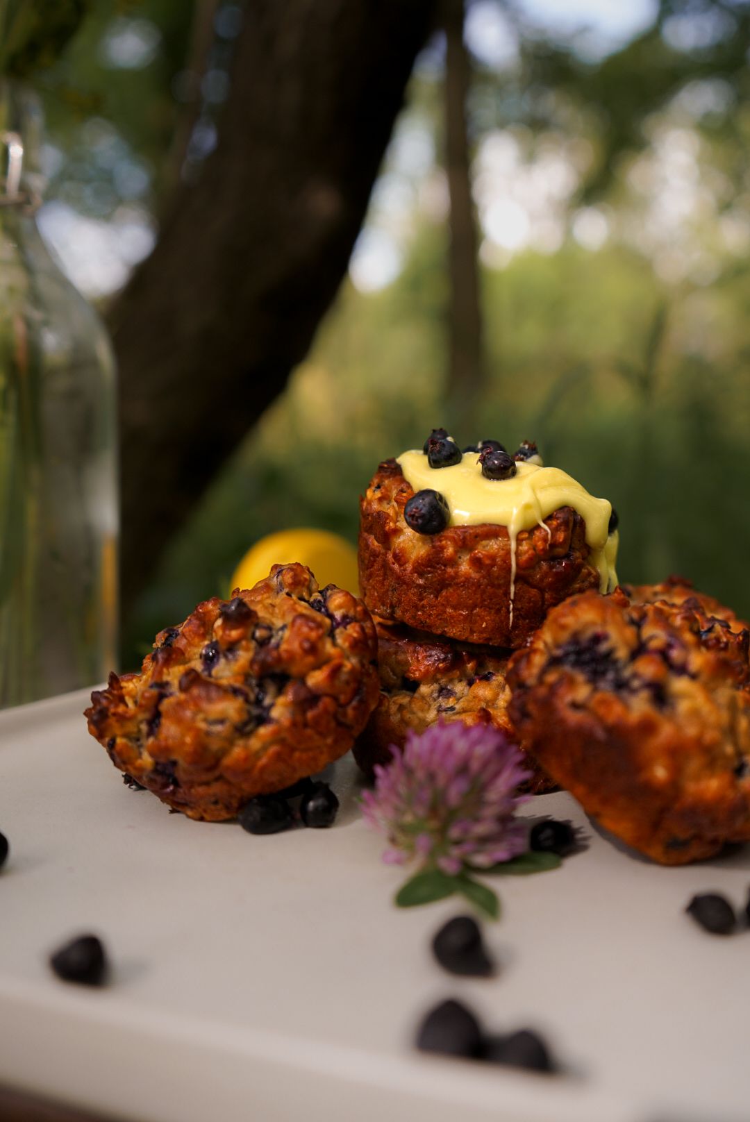 Golden brown baked pastries topped with fresh blueberries and purple flowers on a white surface.
