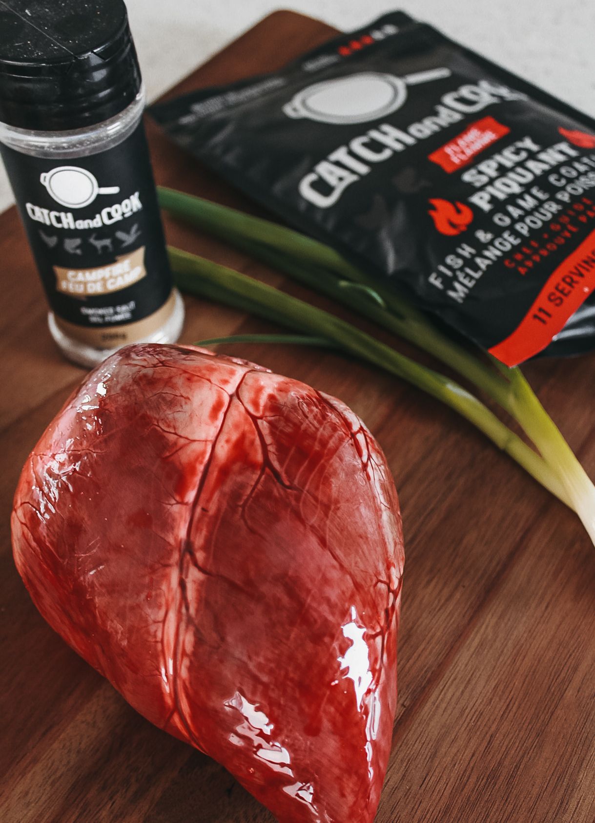 Raw red meat sealed in vacuum packaging on a wooden cutting board.