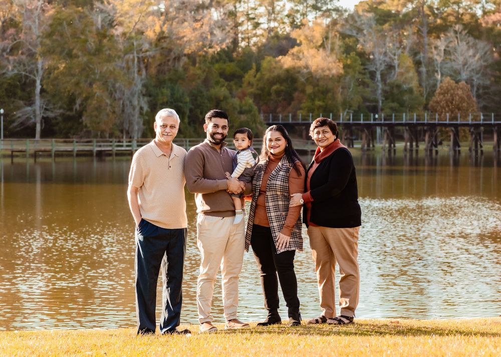 Group of people walking together along a lake shore in autumn with golden leaves on the ground.