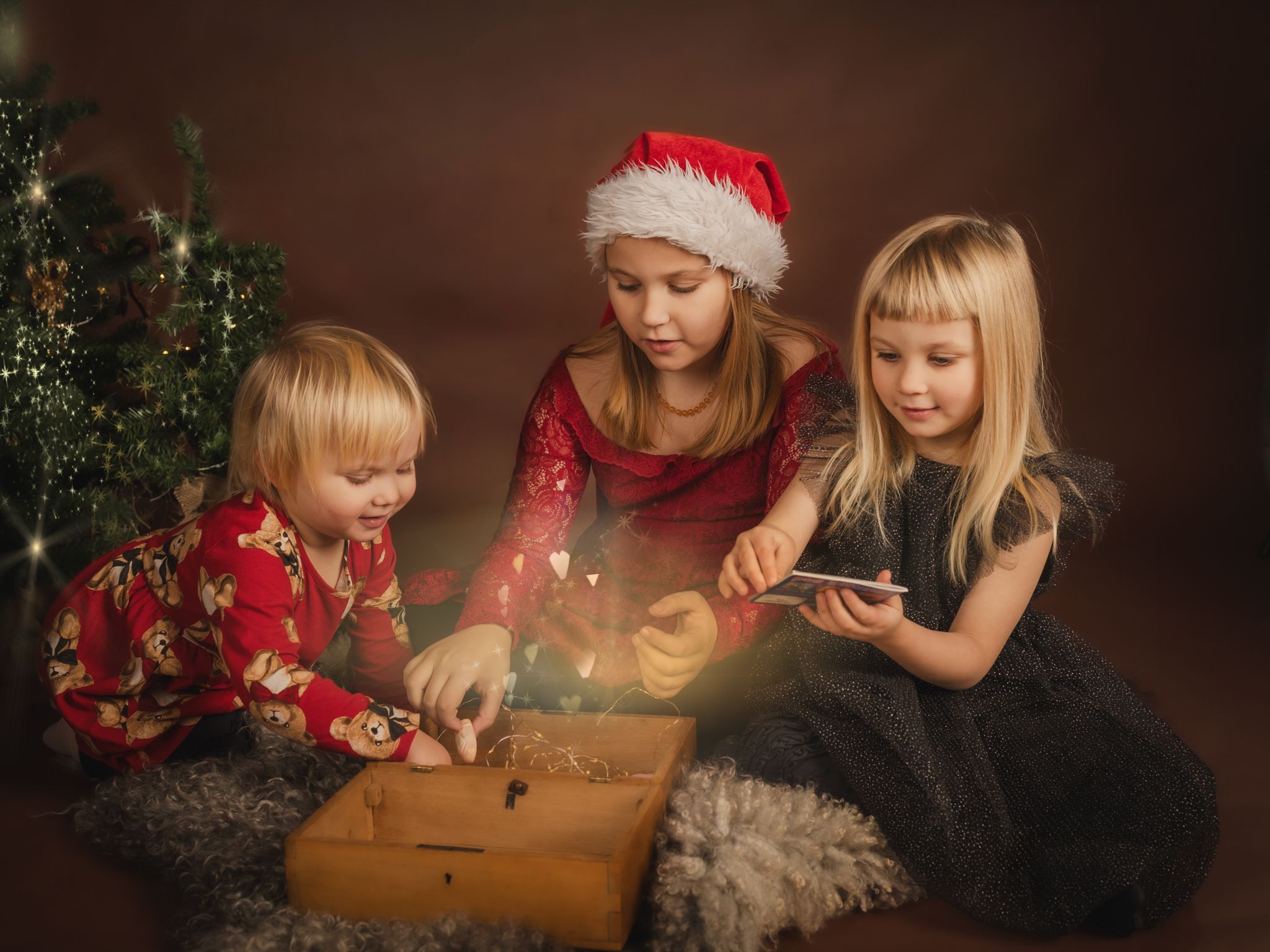 A warm holiday scene with people sitting by candlelight near a decorated Christmas tree.