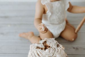 Close-up of white frosted cake on wooden floor during cake smash session.