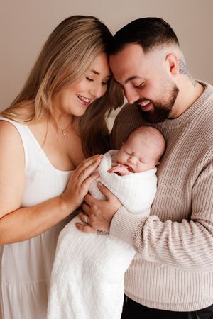 Loving family photos showing parents bonding with newborn baby in soft beige tones. Captured in a natural light studio in the blue mountains