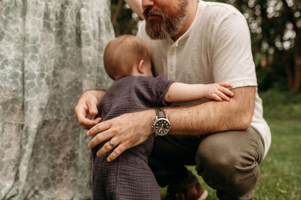 A little boy climbs into his father arms for snuggles in the middle of family photos in St. Louis county, MO.
