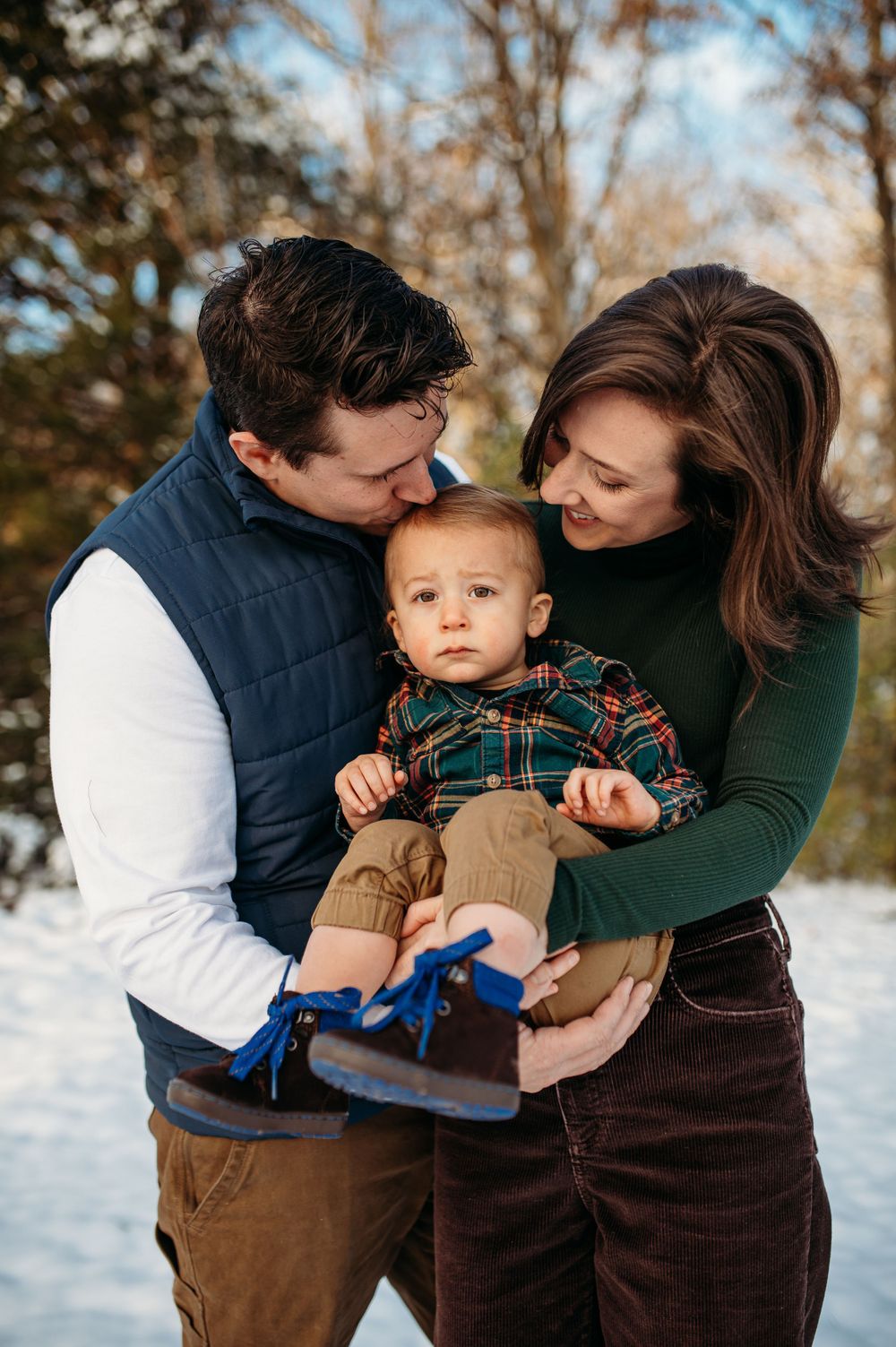 Mom and dad snuggle their toddler as they laugh and enjoy having their family photos taken in St. Charles county, MO.