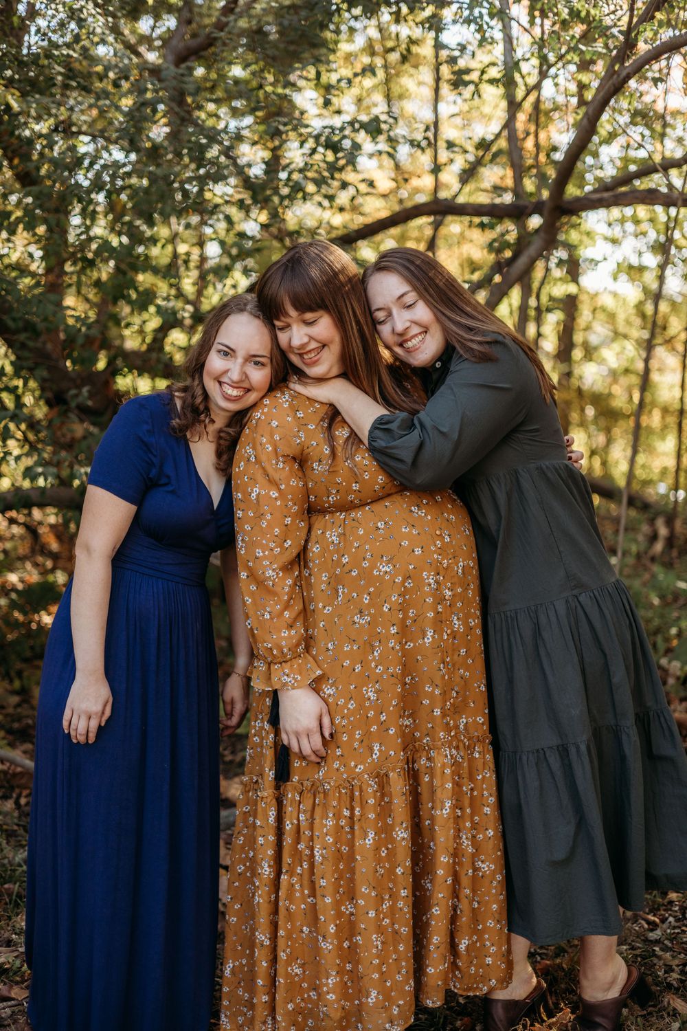 Three adult sisters snuggle and pose for pictures with big smiles on their faces during a photoshoot in St. Louis, MO.