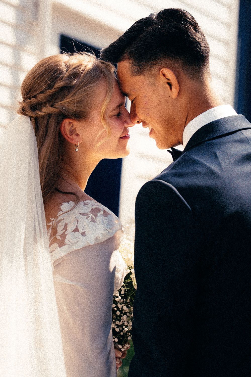 Bride and groom touch foreheads intimately in a tender close-up portrait on their wedding day.
