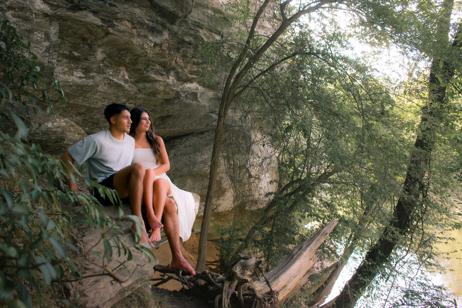 Couple poses for romantic photos near rocky cliffs and water.