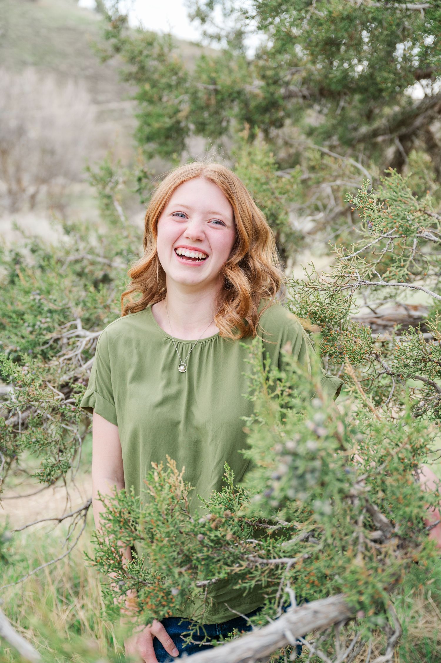Portrait in a natural outdoor setting with greenery and sunlight filtering through trees.