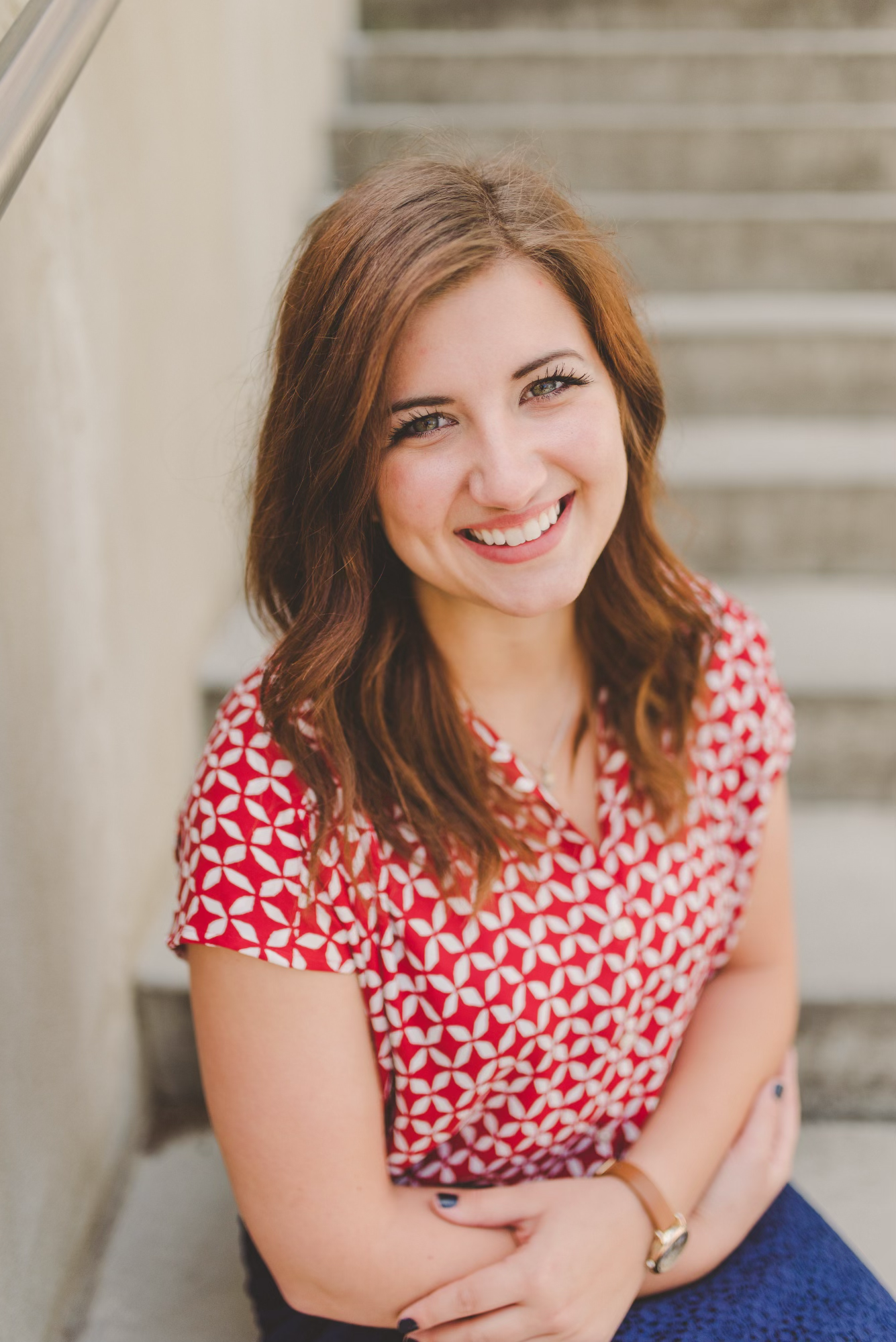 Portrait against stone stairway wearing red and white patterned top.