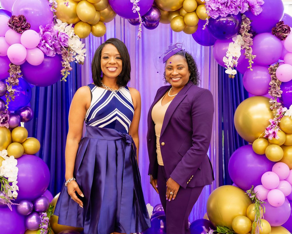 Elegant event setup with purple and gold balloon garlands framing a formal backdrop.