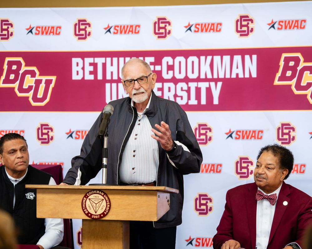 Speaker addresses audience at podium during university press conference.