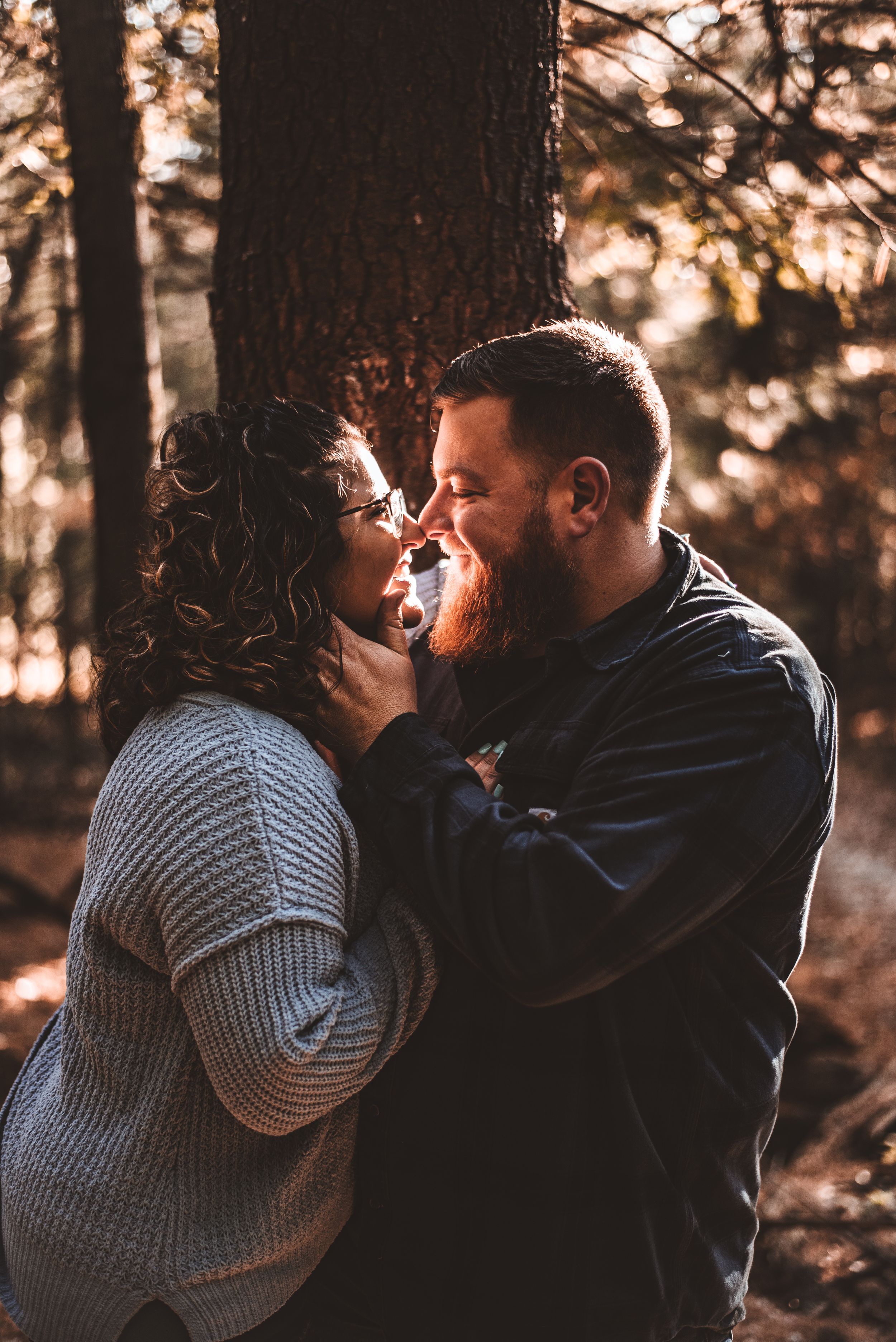 Intimate close-up of couple about to kiss in sunlit autumn forest.