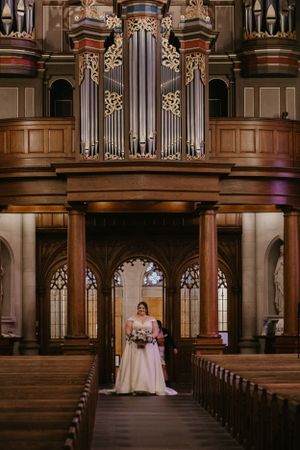 A stunning church interior with ornate organ pipes and Gothic architecture features illuminated wooden details and pews.