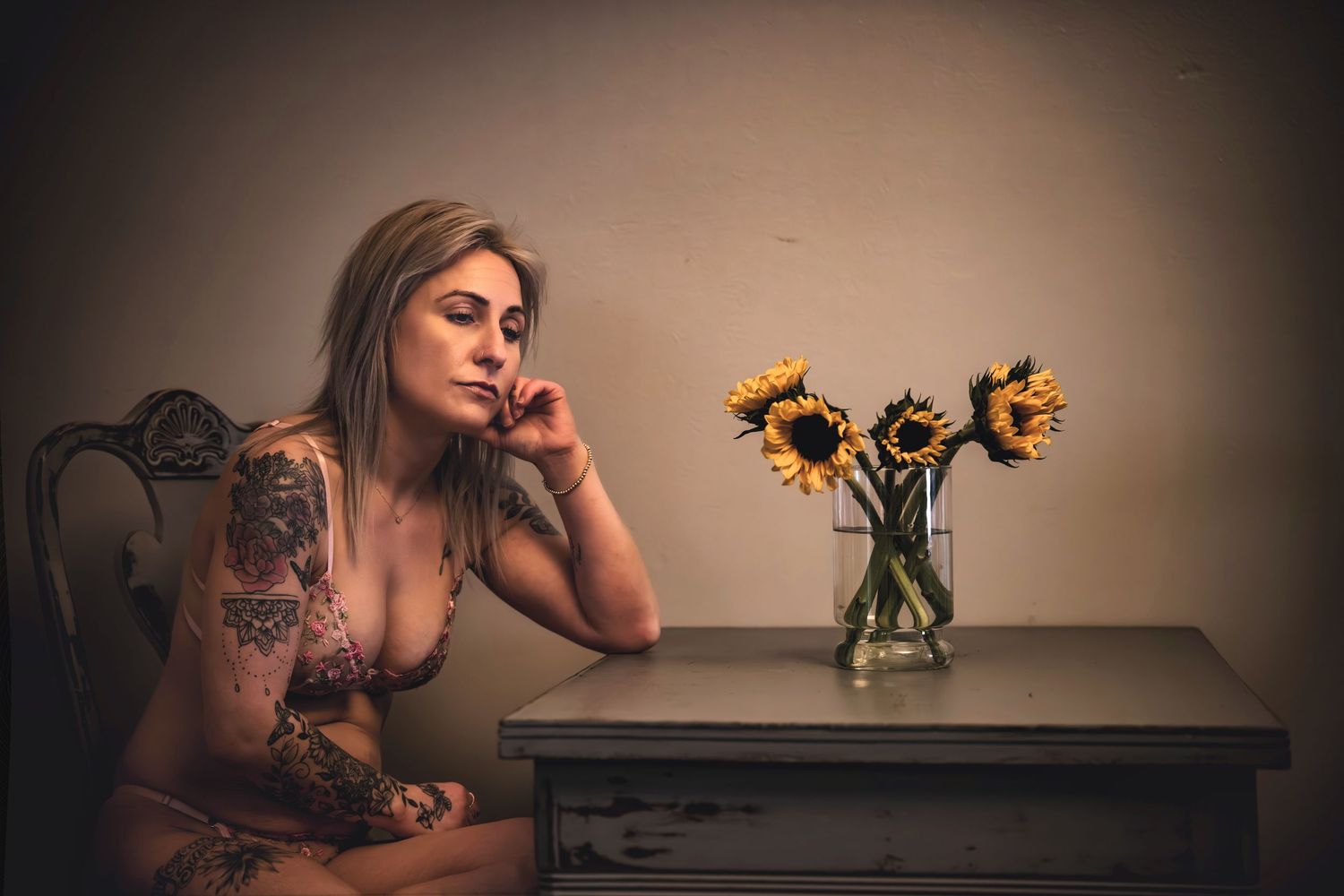 Moody portrait with sunflowers in vase on wooden table.