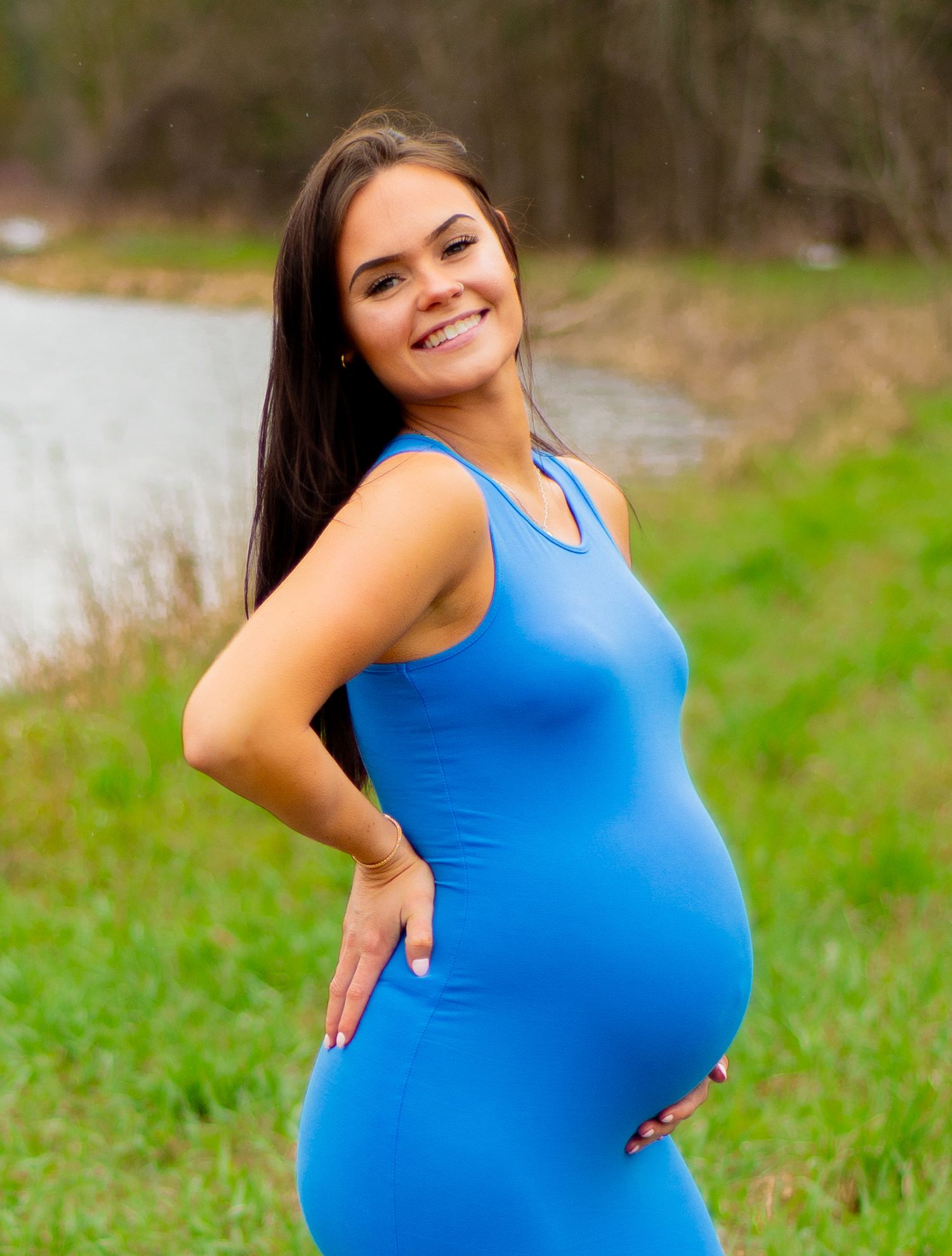 A joyful maternity portrait in a bright blue dress by the water.